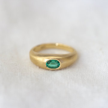 Oval emerald bezel set in 18k gold domed band