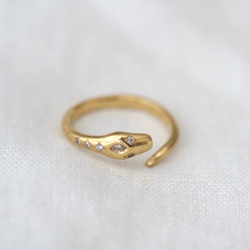 a gold snake that wraps around the finger, with white diamond eyes, a marquise cut diamond on its head, and additional three white round diamonds down its back
