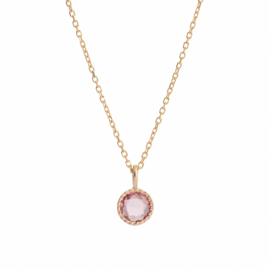 A sweet pink sapphire sits in a milgrain setting on an 18 inch 14k gold chain