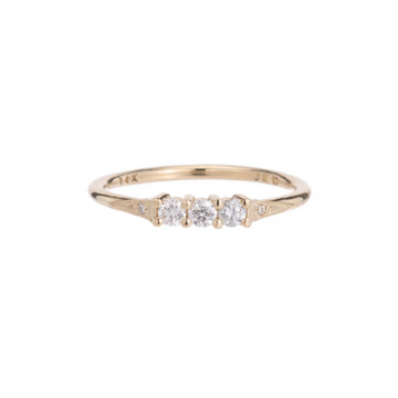 Three white diamonds prong set in a 14k gold band, set between two milgran triangle shaped details with two smaller white diamonds