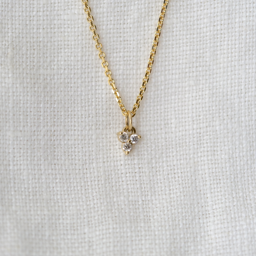 Three small white diamonds prong set in a triangle configuration, hanging on a sixteen inch 14k chain