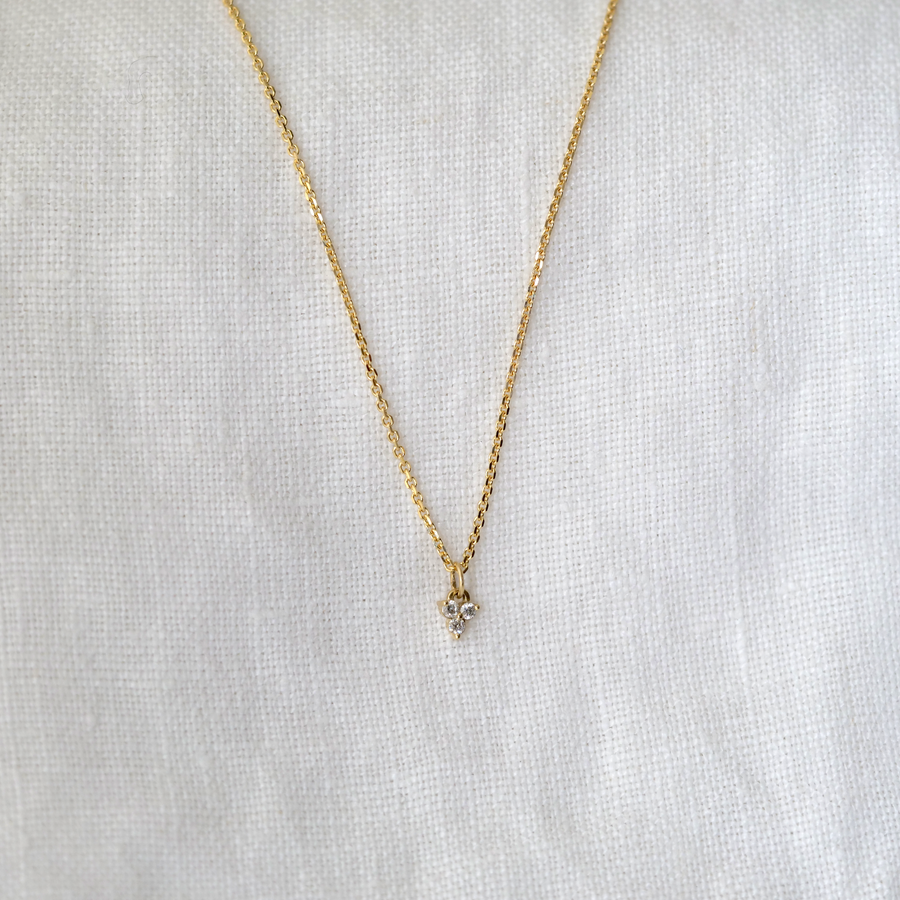 Three small white diamonds prong set in a triangle configuration, hanging on a sixteen inch 14k chain