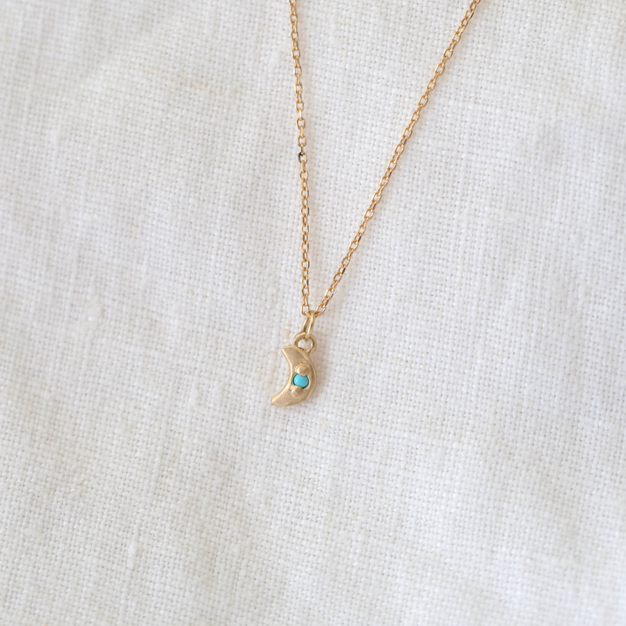 small gold moon with bead set turquoise point in the center, on delicate gold chain