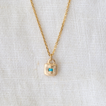 Small gold square pendant with bead set turquoise point in the center on delicate gold chain