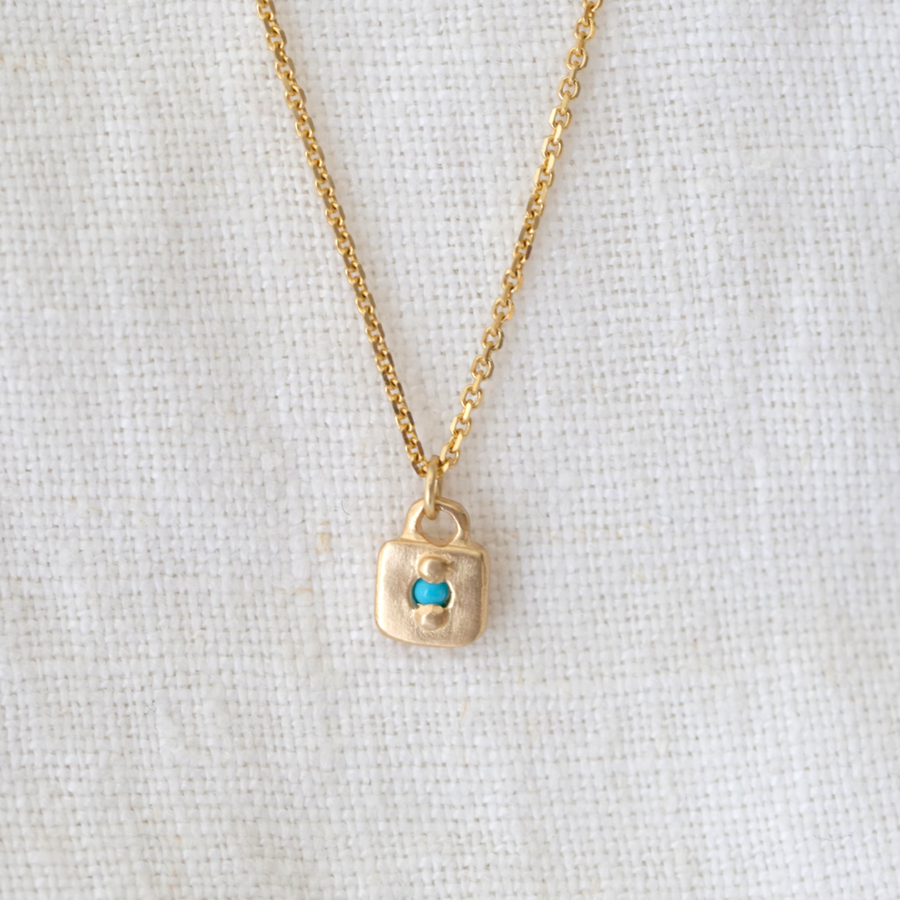Small gold square pendant with bead set turquoise point in the center on delicate gold chain