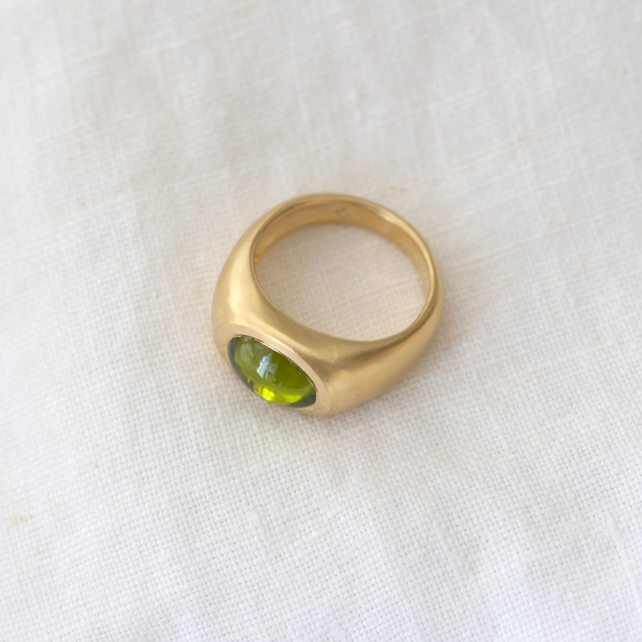 lustrous 18K gold, this chunky power ring features a dramatic peridot cabochon that glimmers with spectacular colors in any lighting