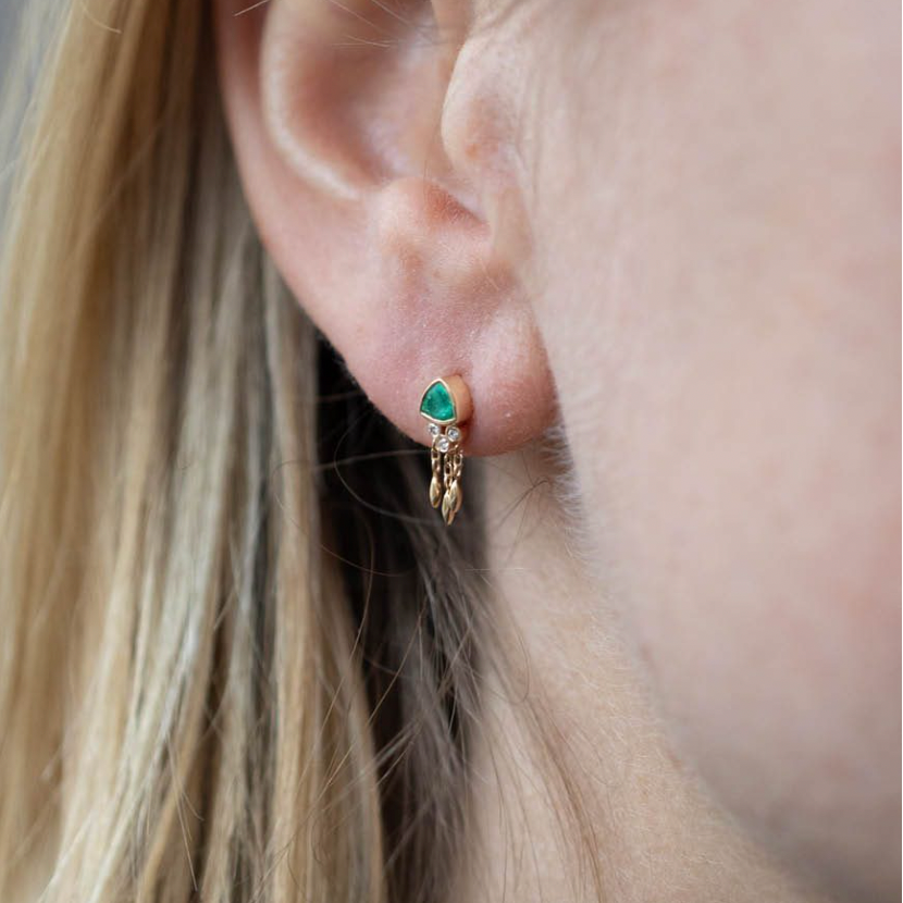 Celine Daoust 14k light yellow gold earring with one green emerald, diamonds and dangling gold details.