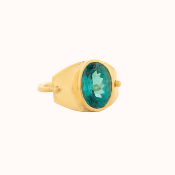 Large oval teal green tourmaline in a high bezel setting on a wide gold shield. The plate is hinged on a thin gold band.