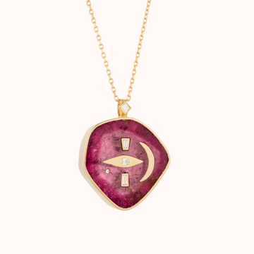 Organically shaped pink tourmaline bezel set in 14k gold, inlayed with diamonds creating an eye, and a gold crescent moon inlayed next to it