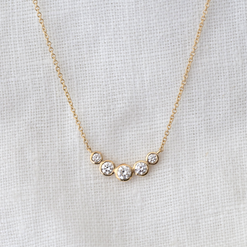 This delicate necklace features a playful arc of five bezel-set white diamonds on a 14k gold chain.