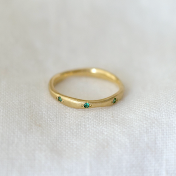 Wavy natural eternity band in 18k yellow gold, with eight 1.7mm emerald set around the band