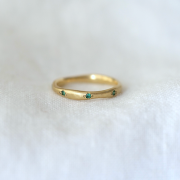 Wavy natural eternity band in 18k yellow gold, with eight .7mm emerald set around the band