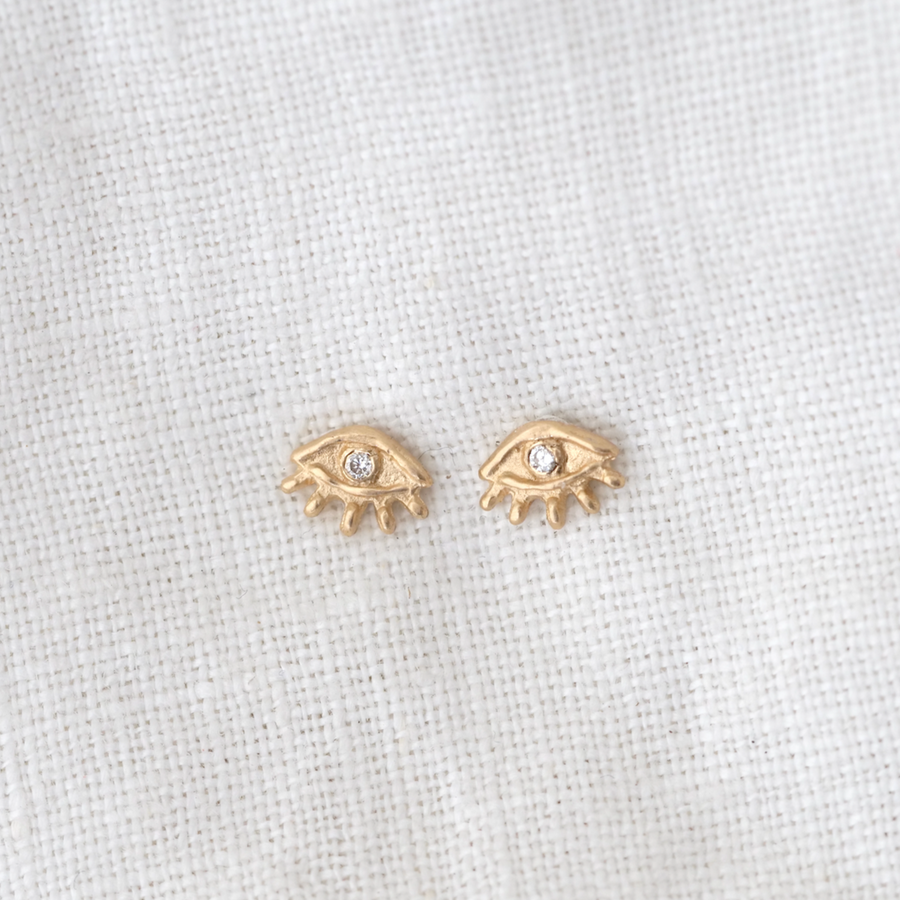 14k eye shaped stud earrings with Little bitty lashes rim the lower half, while the white diamond stone acts a pupil