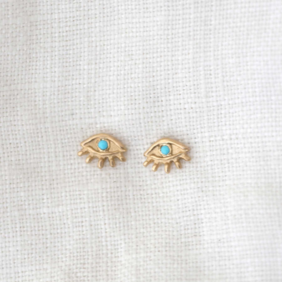 14k eye shaped stud earrings with Little bitty lashes rim the lower half, while the turquoise stone acts a pupil