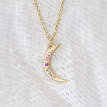 14k crescent moon pendant with pink, purple and blue gemstones bead set between gold granulation details down the length of the moon 