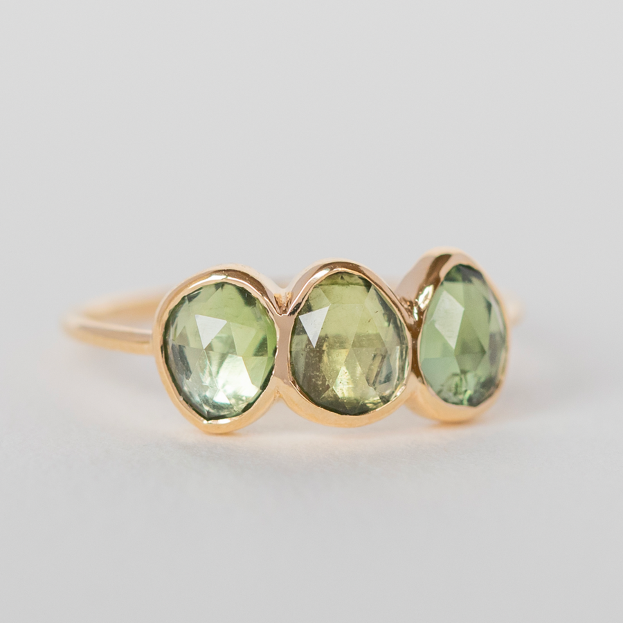 Three light green tourmaline stones, organically cut and bezel set on a think gold band