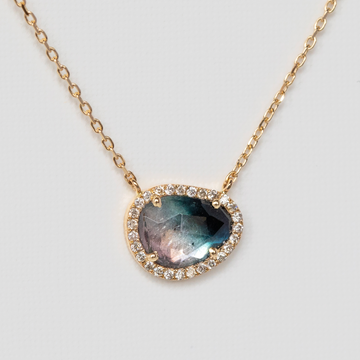 Organically shaped green tourmaline that fades from light pink to dark blue, with white diamonds set all around the stone, on delicate gold chain