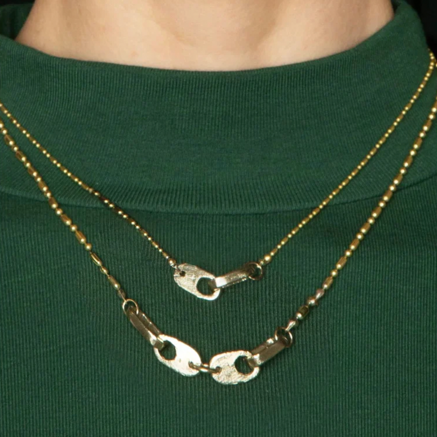 inked pendant on a brass bead-chain that mirrors the shapes in the links on model