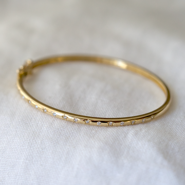 A solid but refined 14k bangle, set with 17 diamonds, alternately bezel and star set