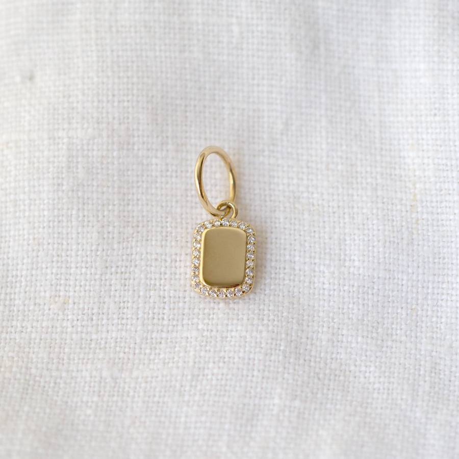 mini dogtag-style piece is set with a halo of pave white diamonds