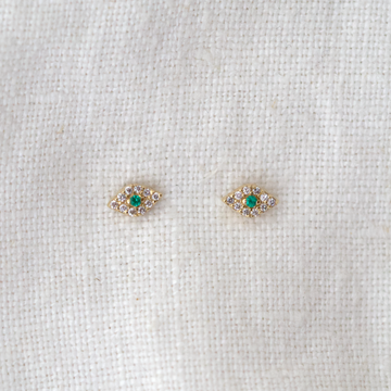 white diamonds pave set in 14k gold around a green emerald, making an eye shaped stud