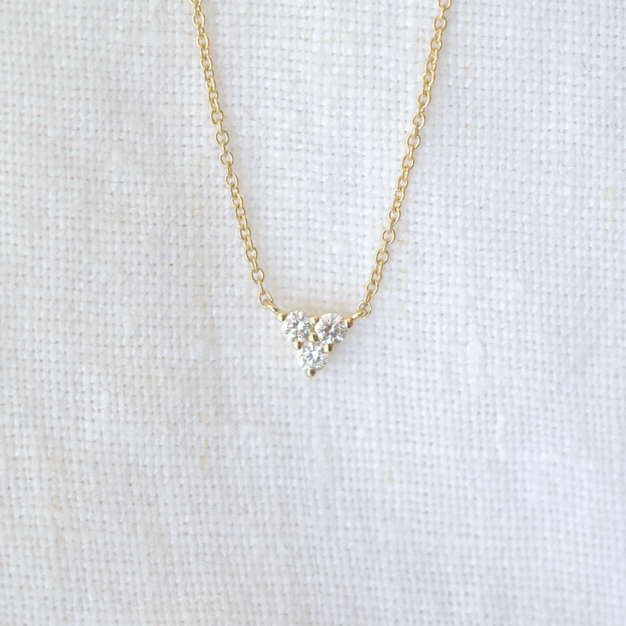 Three white diamonds prong set in the shape of a triangle, on a delicate gold chain 