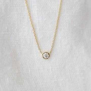 delicate gold chain features a bezel set diamond solitaire