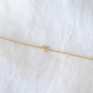 delicate gold chain features a tiny gold heart with a small diamond