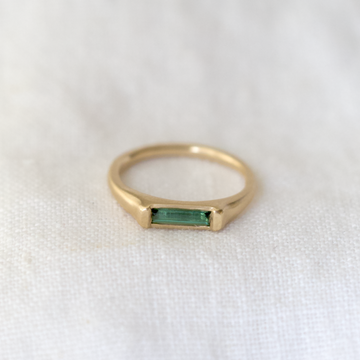 A slim rounded gold band with a signet like face made of a beautiful tourmaline bar