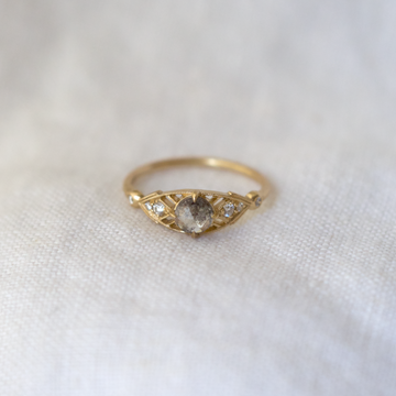 A marquis shape mounting with a salt and pepper rose cut diamond sits within a delicately pierced deco framework on a thin gold band