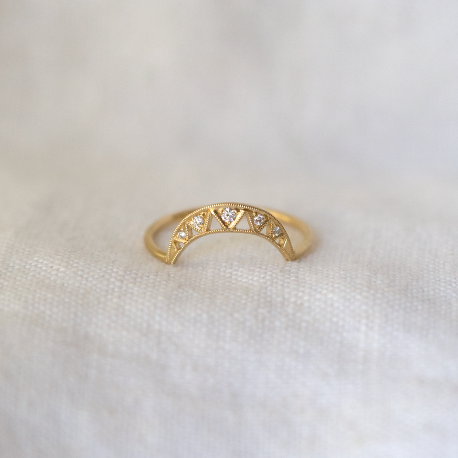 This band has a crescent shaped arch with five small diamonds in bright cut settings