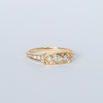 this ring combines trillion cut and square cut diamonds in a geometric design on a dainty signet-style plate with crescent details and brilliant cut diamonds extending from the band