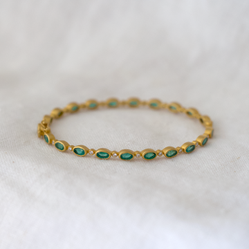 21 oval emeralds are interspersed with 20 white diamonds, all set in a rich, matte 18k bangle