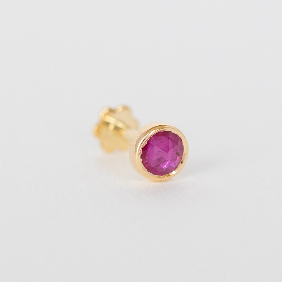 14K LIGHT YELLOW GOLD PIERCING WITH A ONE OF A KIND RUBY STONE. THE STONE COMES IN A GRADIENT OF REDDISH PINK.