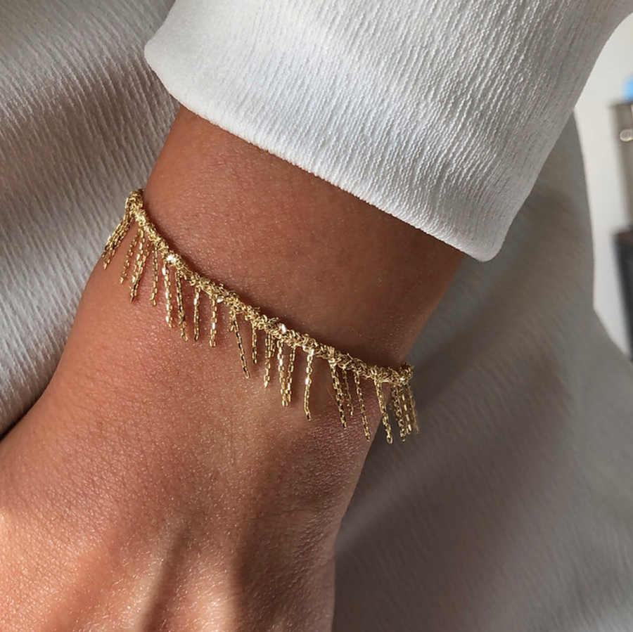 gold chain woven in the bracelet, with small tassels coming off of it 