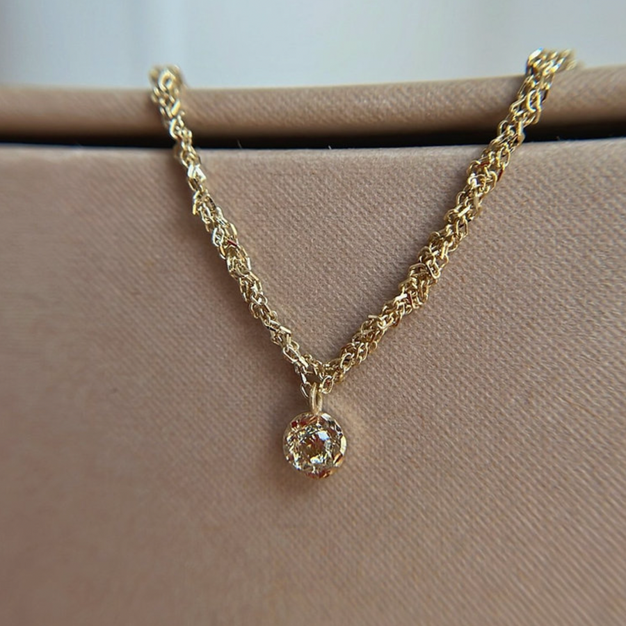 14k gold woven chain necklace with small pendant at the center, set with a warm brown Champagne diamond. 