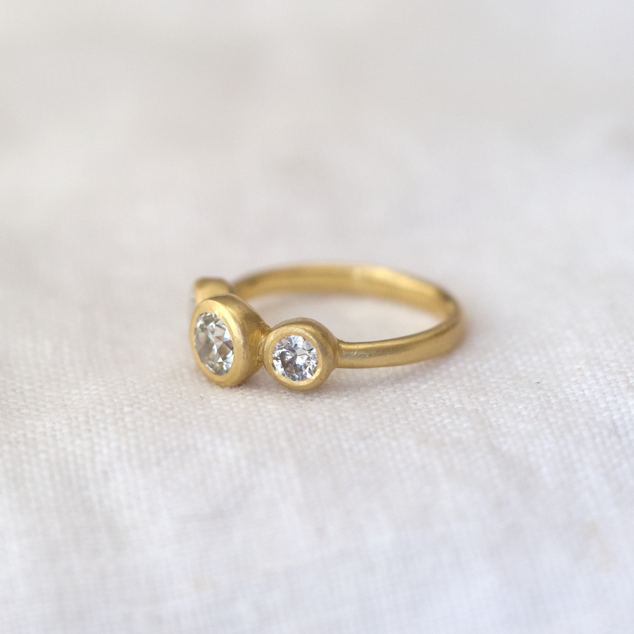 Gold ring with two round gemstones on a white fabric background