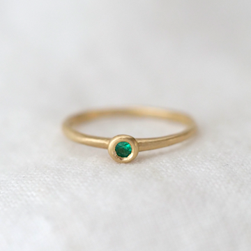 round green emerald bezel set in 14k gold on a simple gold band