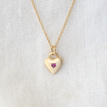 14k gold heart pendant with ruby cabochon bead set in the center, on a delicate gold chain 