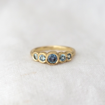 5 stunning Montana Sapphires in a stunning oceanic teal hue, bezel set in hand-carved and cast 18k gold.