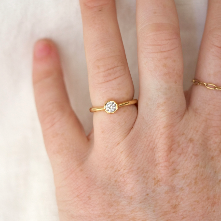 solitaire diamond bezel set in 18k gold on a tapped 18k band, on model 