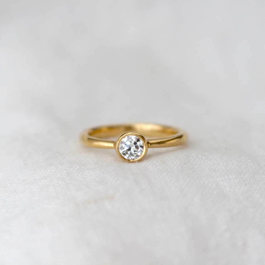 solitaire diamond bezel set in 18k gold on a tapped 18k band 