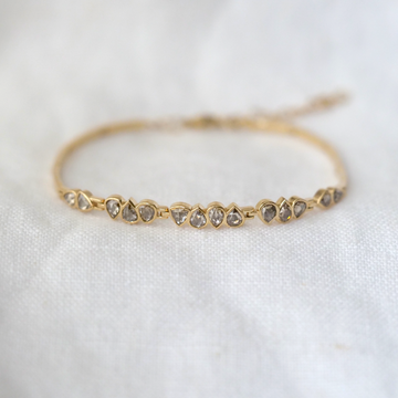 triangular grey diamonds bezel set in groups of 2, 3 and 4, on an articulated 14k gold bracelet