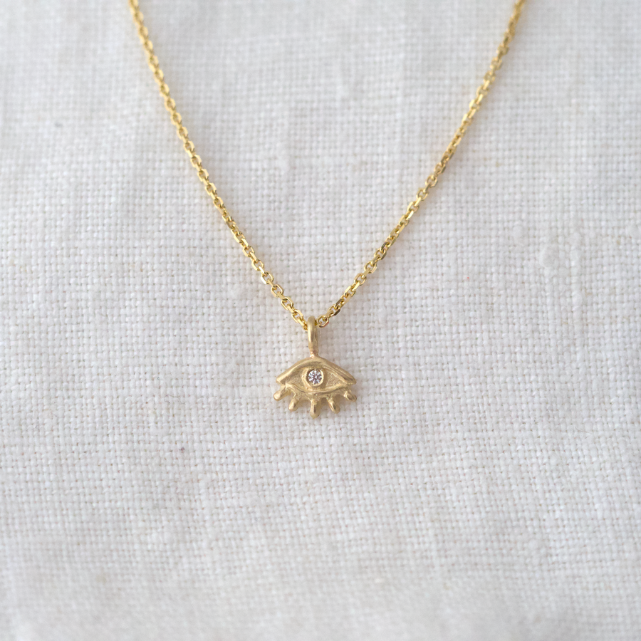 solid gold eye pendant with white diamond set in the center, on a delicate 14k chain