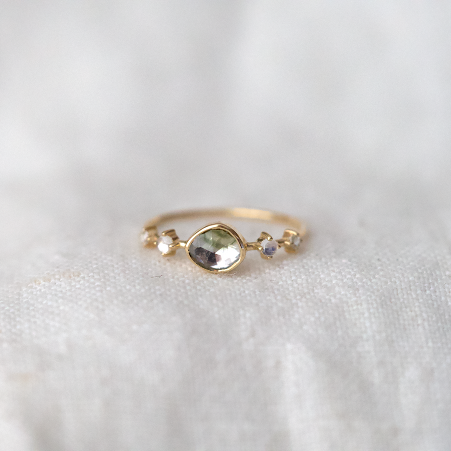 14k yellow gold ring with a green and grey tourmaline center stone, and smooth moonstone and rose-cut diamond side stones