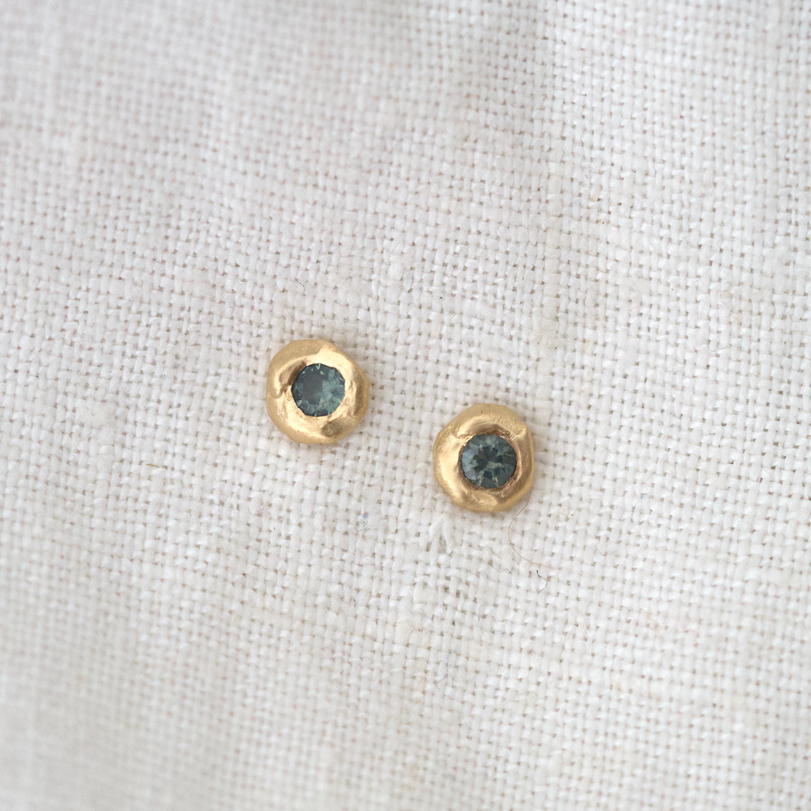 These little studs are organically shaped of gold with dark sapphire flush set in the center