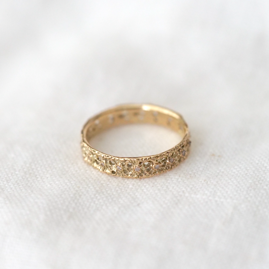 A ring with a lace motif. This is an eternity type ring with small diamonds all around, adding a subtle sparkle to a simple gold band. 