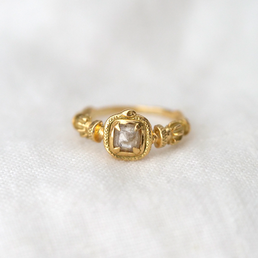 Absolutely breathtaking in its quiet, intricate detail, this solitaire ring exudes a subtle, earthy presence. The rose cut center diamond is surrounded by tiny milgrain detailing in the rich yellow gold.