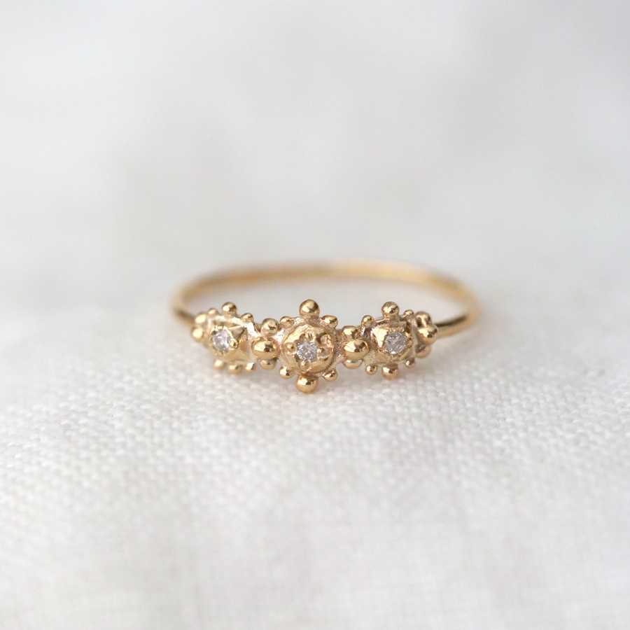 Three organic gold circles with small gold granulation around each one and a white diamond in the center.