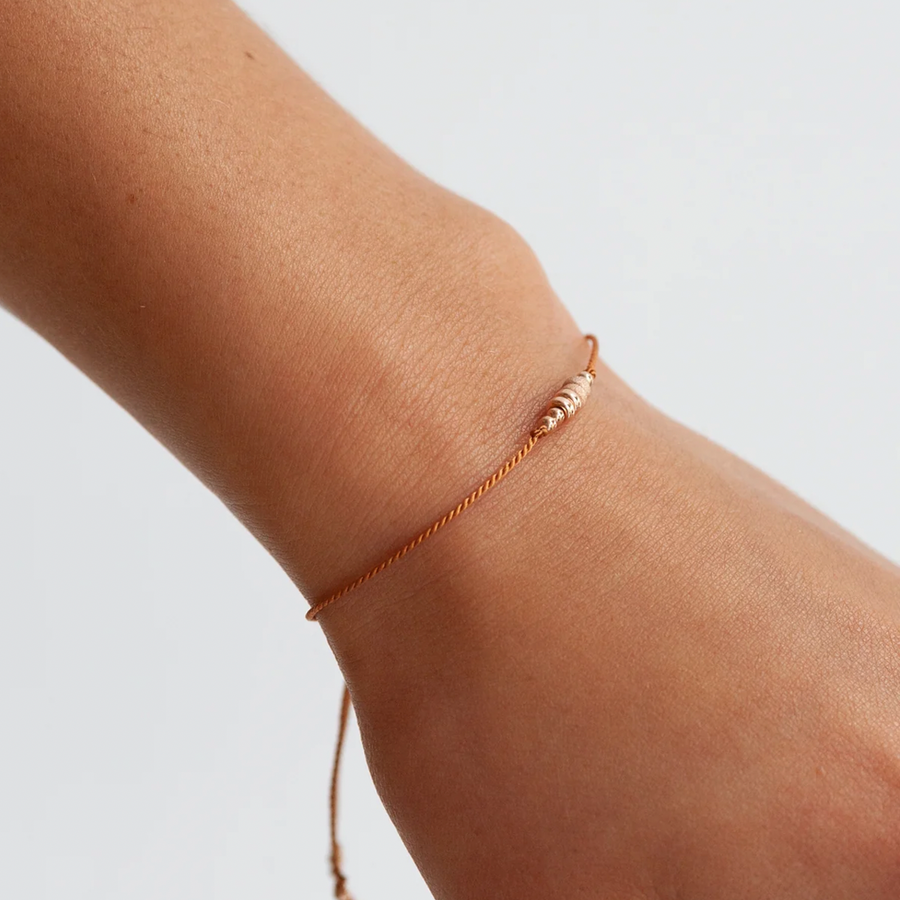 simple TAN silk cord bracelet adorned with smooth and shimmery textured 14k rose gold-filled beads., ON MODEL